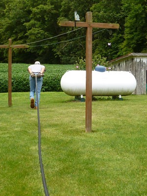 Picture of man dragging hose to refill propane tank.